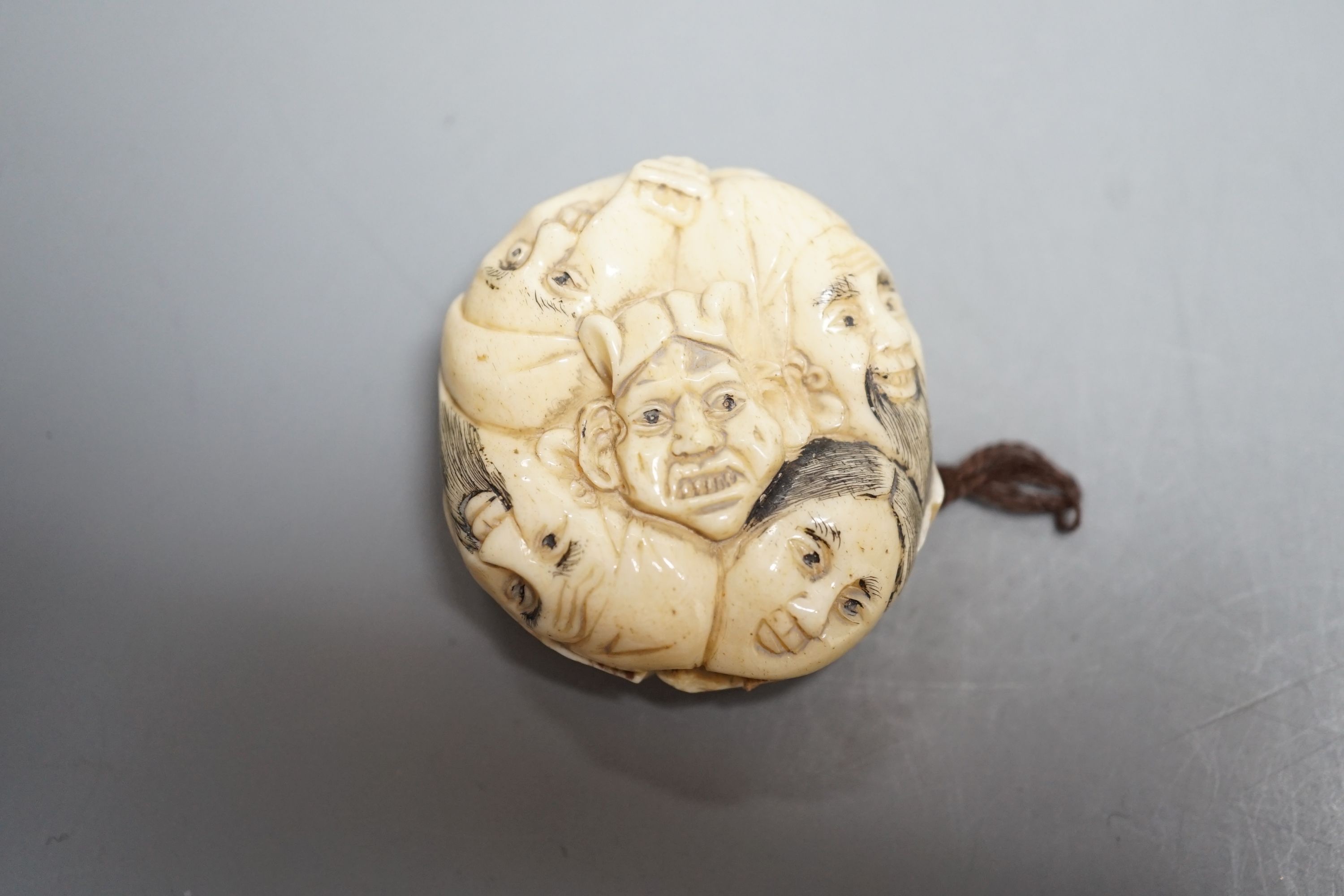 A Japanese ivory netsuke of a man reading a book, a small okimono of Guanyin and monkeys, a Manju netsuke of masks and an early 20th century netsuke of a bearded man